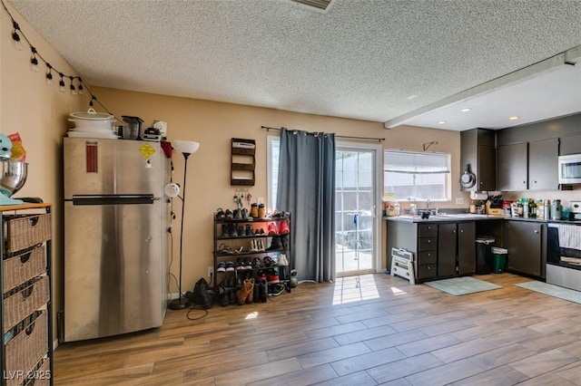 kitchen featuring stainless steel appliances, a textured ceiling, light wood finished floors, a sink, and recessed lighting