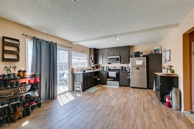 kitchen featuring stainless steel appliances, a textured ceiling, light wood-style flooring, and light countertops