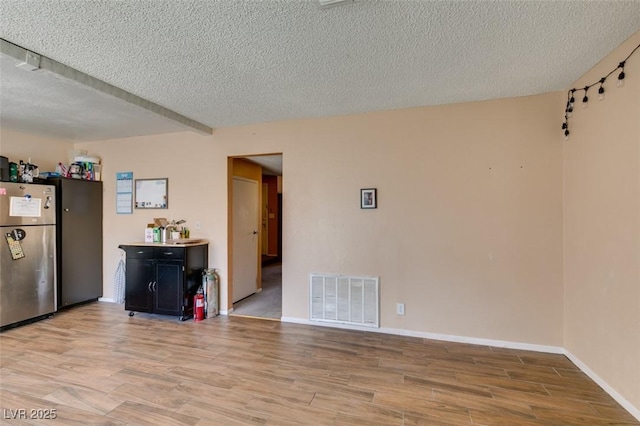 empty room with a textured ceiling, wood finished floors, and baseboards