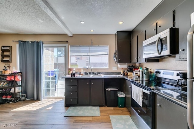 kitchen featuring stainless steel appliances, a sink, a textured ceiling, light wood finished floors, and recessed lighting