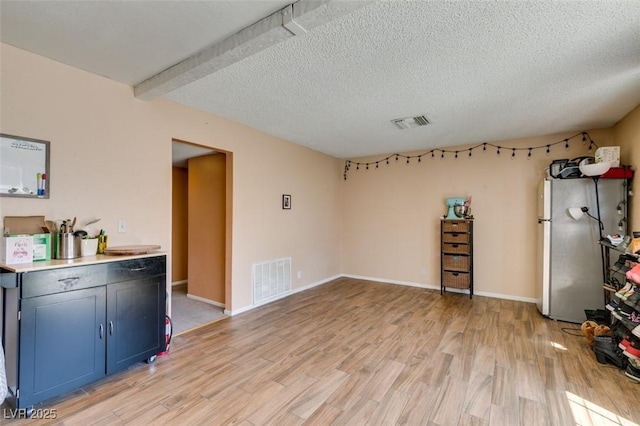 interior space with light wood-style flooring, a textured ceiling, and baseboards