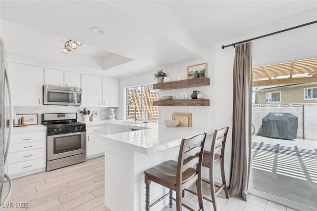 325 Heather Dr, Henderson, NV 89002 - kitchen with stainless steel appliances, a sink, a peninsula, open shelves, and light countertops