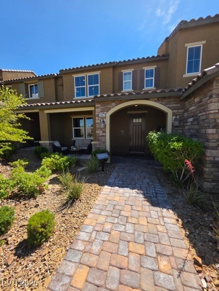view of front of house featuring stucco siding, a tile roof, and stone siding