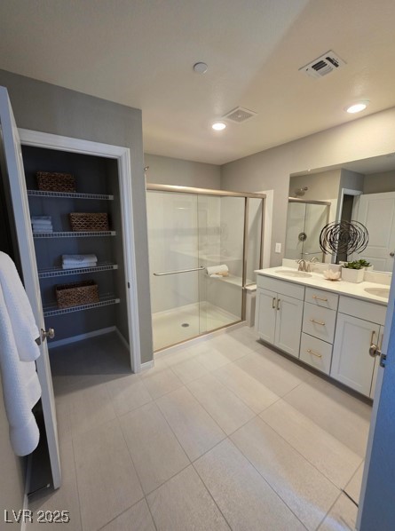 full bathroom with a stall shower, double vanity, and recessed lighting