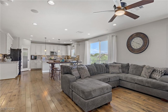 living area with a ceiling fan, hardwood / wood-style floors, and recessed lighting
