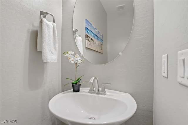 bathroom featuring a sink and a textured wall