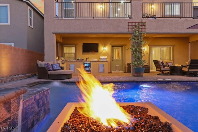 view of swimming pool featuring a patio, fence, and an outdoor living space with a fire pit