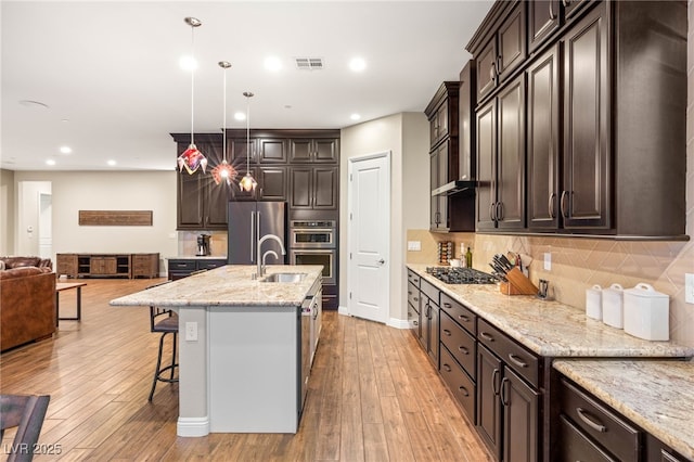 2116 Canvas Edge Dr, Henderson, NV 89044 - kitchen with stainless steel appliances, open floor plan, a sink, light wood-style flooring, and dark brown cabinetry