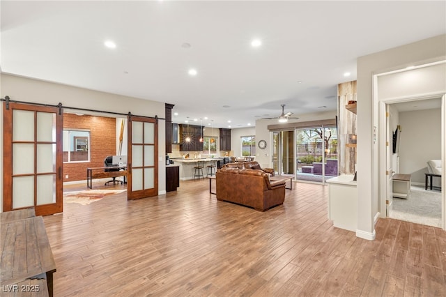 2116 Canvas Edge Dr, Henderson, NV 89044 - living area featuring a barn door, recessed lighting, light wood-style flooring, a ceiling fan, and baseboards