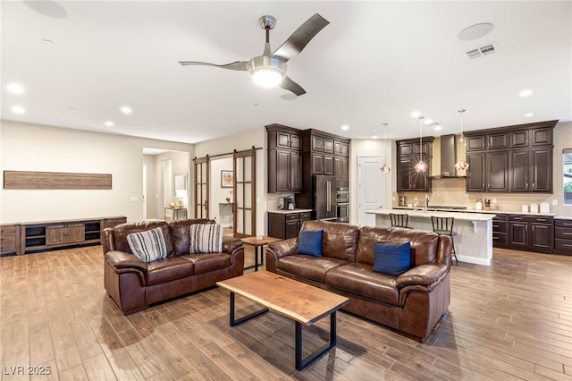2116 Canvas Edge Dr, Henderson, NV 89044 - living area featuring light wood-style floors, a ceiling fan, a barn door, and recessed lighting