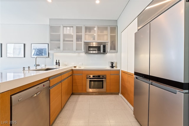 3726 Las Vegas Blvd Unit 2410, Las Vegas, NV 89158 - kitchen featuring stainless steel appliances, a sink, light countertops, glass insert cabinets, and brown cabinetry