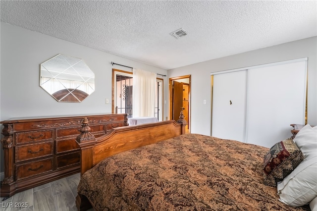 bedroom with dark wood-style floors, a closet, and a textured ceiling