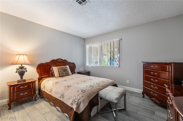 bedroom featuring baseboards, wood finished floors, and a textured ceiling