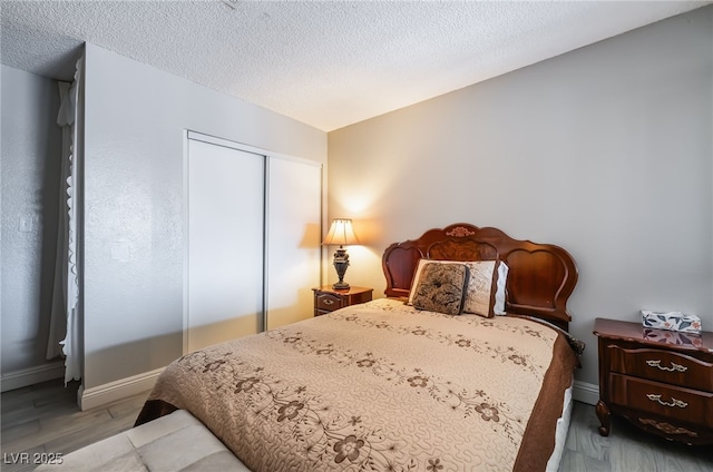 bedroom with a closet, wood finished floors, baseboards, and a textured ceiling
