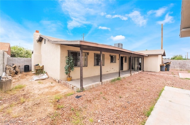 rear view of property with a patio, stucco siding, fence, and a chimney