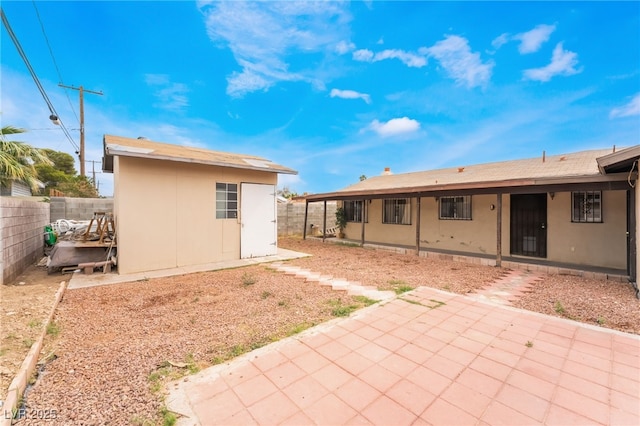 back of property with a patio, a fenced backyard, and an outdoor structure