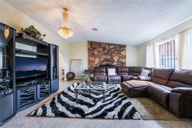 tiled living area featuring vaulted ceiling, arched walkways, and a textured ceiling