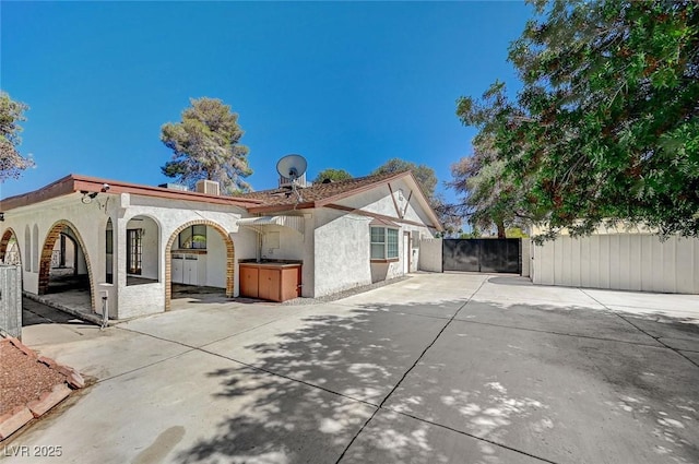 view of front of property featuring stucco siding, fence, a gate, and central AC
