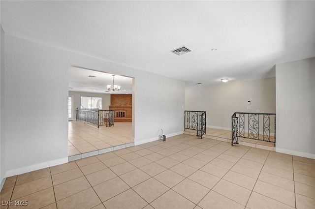 spare room featuring a chandelier, light tile patterned floors, and baseboards