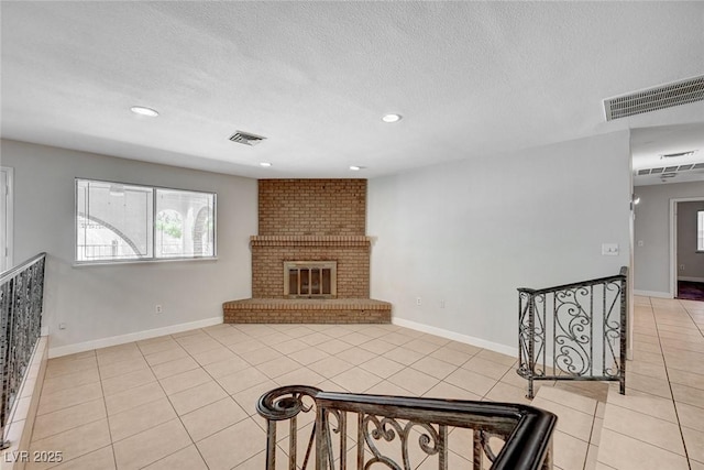 unfurnished living room with light tile patterned floors, recessed lighting, a textured ceiling, baseboards, and a brick fireplace