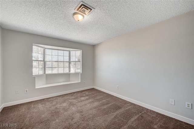 spare room featuring dark colored carpet, a textured ceiling, and baseboards