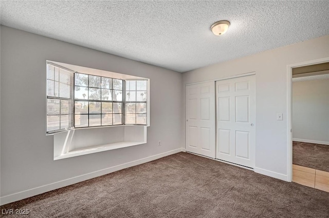 unfurnished bedroom with carpet floors, a textured ceiling, a closet, and baseboards