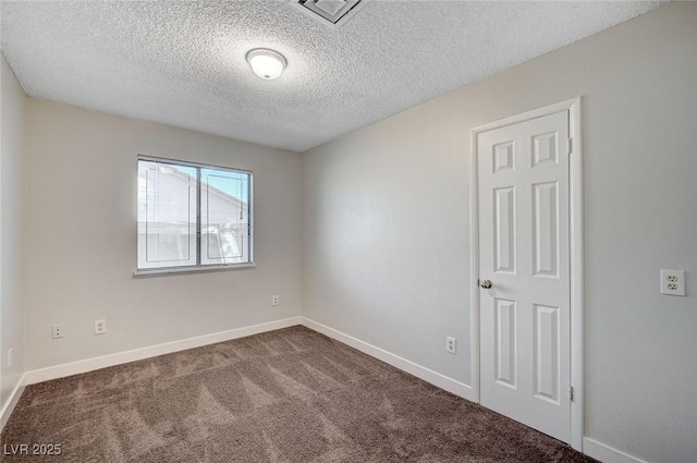 unfurnished room with a textured ceiling, dark colored carpet, and baseboards