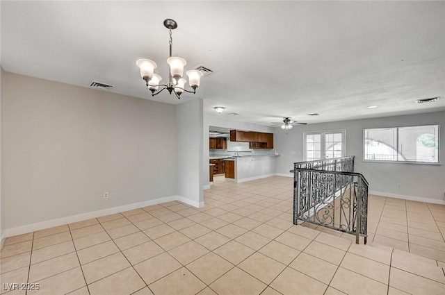 empty room with a chandelier, light tile patterned floors, ceiling fan, and baseboards