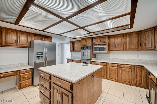 kitchen with stainless steel appliances, light tile patterned floors, a center island, and brown cabinetry