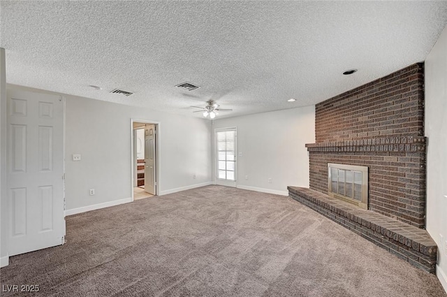 unfurnished living room featuring ceiling fan, carpet floors, a brick fireplace, baseboards, and a textured ceiling