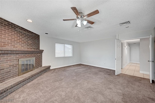 unfurnished living room with carpet floors, a ceiling fan, a textured ceiling, a brick fireplace, and baseboards