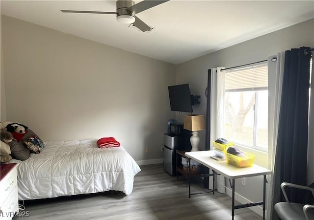 bedroom featuring baseboards, wood finished floors, and a ceiling fan