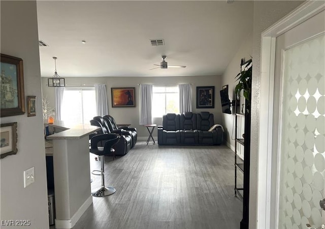 living room featuring wood finished floors, baseboards, and a ceiling fan