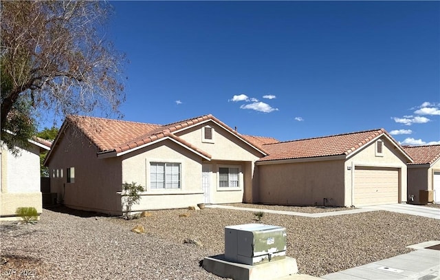 single story home with stucco siding, a tile roof, an attached garage, and concrete driveway