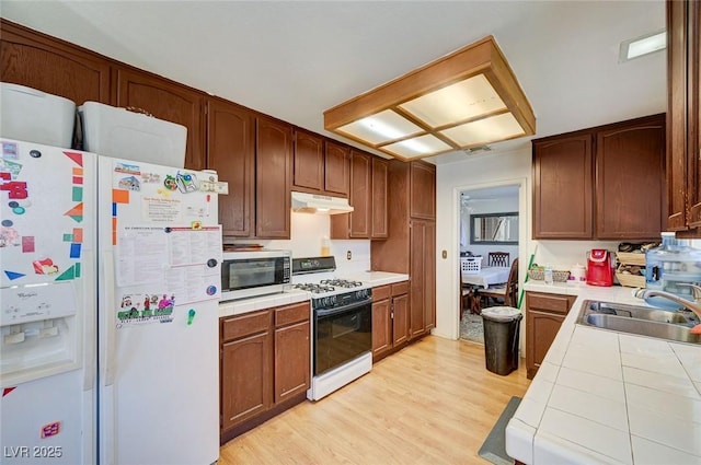 3138 White Rose Way, Henderson, NV 89014 - kitchen with white appliances, under cabinet range hood, tile counters, and light wood-style flooring