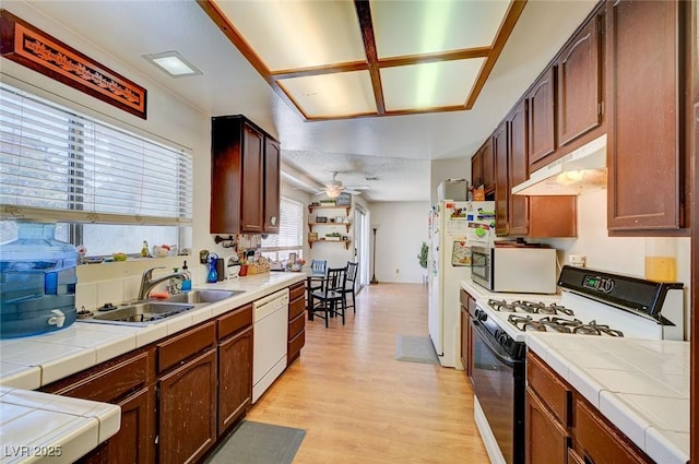 3138 White Rose Way, Henderson, NV 89014 - kitchen with gas range oven, under cabinet range hood, dishwasher, tile countertops, and light wood-style floors