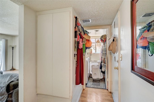 3138 White Rose Way, Henderson, NV 89014 - hallway featuring a textured ceiling, light wood-style floors, healthy amount of natural light, and washer and clothes dryer