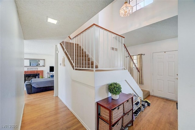 3138 White Rose Way, Henderson, NV 89014 - stairway featuring wood finished floors, a textured ceiling, a brick fireplace, healthy amount of natural light, and a chandelier