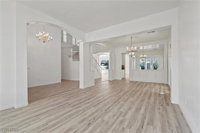 253 White Willow Ave, Las Vegas, NV 89123 - unfurnished living room with a chandelier, arched walkways, wood finished floors, and stairway
