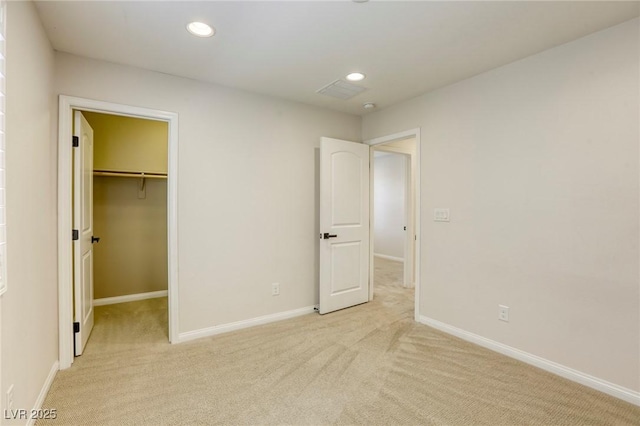 unfurnished bedroom featuring light colored carpet, a spacious closet, recessed lighting, and baseboards