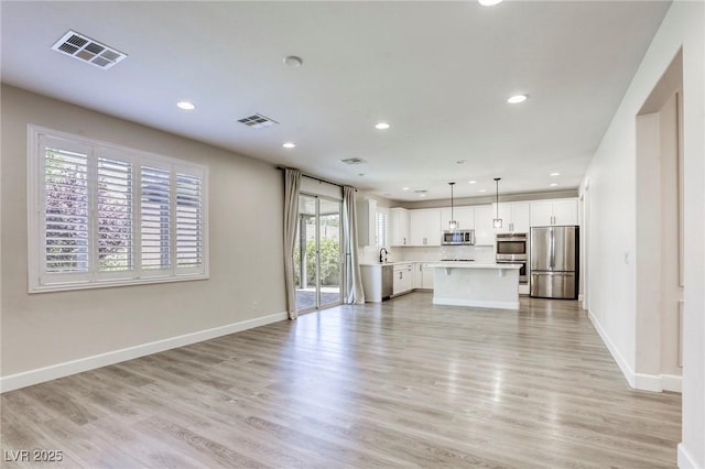 unfurnished living room with recessed lighting, baseboards, light wood-style floors, and a sink
