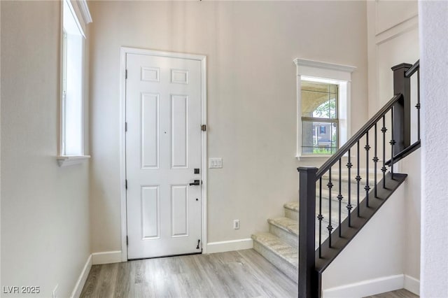 foyer entrance featuring wood finished floors, baseboards, stairway, and a high ceiling