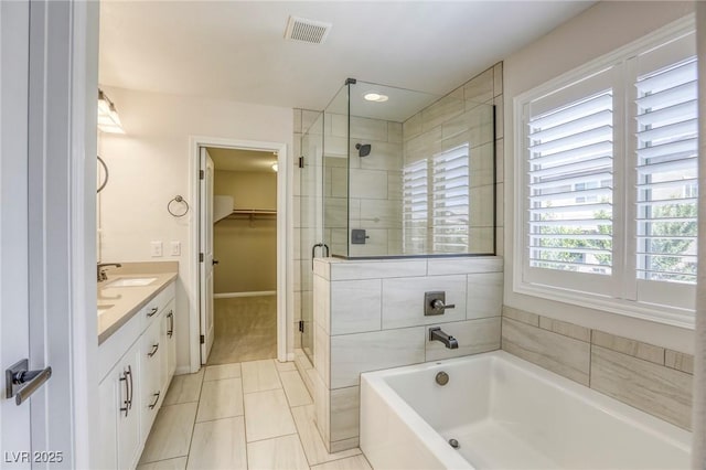 full bathroom with a shower stall, a bath, a spacious closet, vanity, and tile patterned flooring