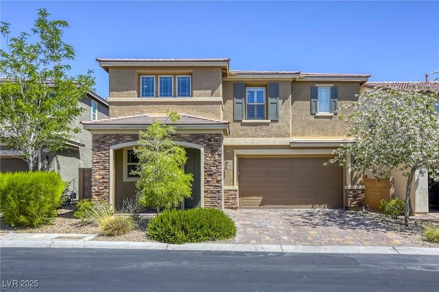 view of front of home with a garage, stone siding, stucco siding, driveway, and a tiled roof