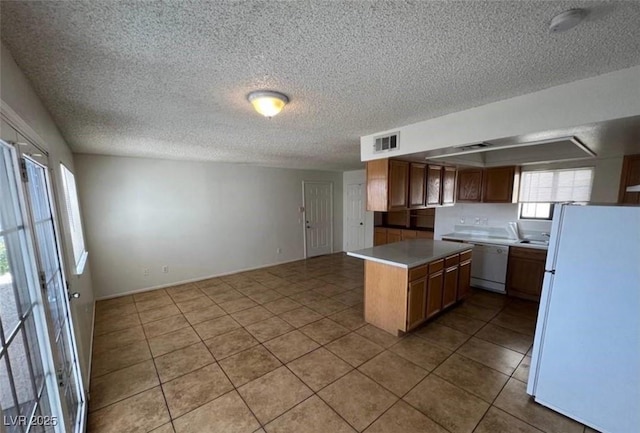 101 Luna Way Unit 145, Las Vegas, NV 89145 - kitchen featuring white appliances, light tile patterned floors, a textured ceiling, open floor plan, and light countertops