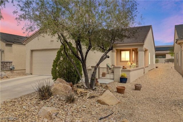 view of front of house with stucco siding, concrete driveway, and an attached garage