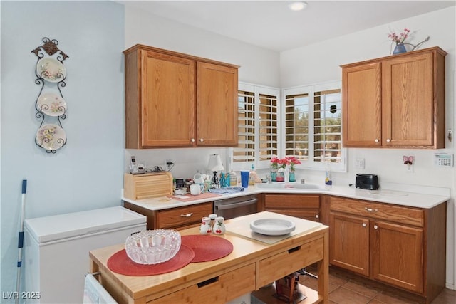 kitchen with a sink, refrigerator, dishwasher, light countertops, and light tile patterned floors