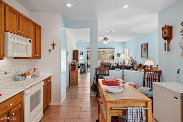 kitchen with white appliances, brown cabinetry, a ceiling fan, light countertops, and light tile patterned flooring