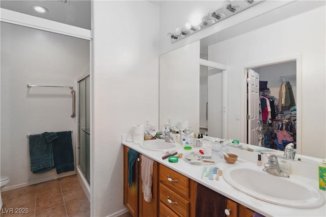 full bathroom with a shower stall, double vanity, tile patterned floors, a walk in closet, and toilet