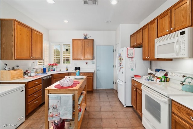 kitchen with white appliances, brown cabinets, light countertops, light tile patterned floors, and recessed lighting